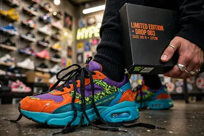 Close-up of limited-edition sneakers on feet against a sneaker-wall backdrop in a hype store, laces undone, box in hand. Sneaker culture photography