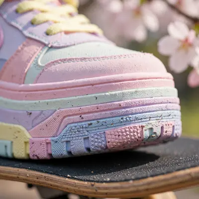 Extreme close-up of platform sneakers in pastel colorway on a skateboard, cherry blossoms blurred behind. Sneaker detail photography, soft spring